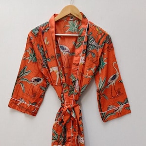 May include: Orange cotton robe with a white trim and a jungle print featuring leopards, birds, and palm trees.