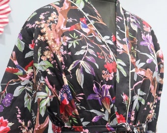 May include: A black floral print robe with a white trim and a tie belt. The robe features a variety of flowers and birds in shades of pink, red, purple, and green.