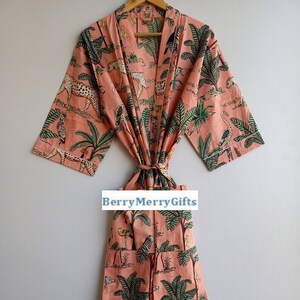 May include: A pink cotton robe with a jungle print featuring leopards, birds, and palm trees. The robe has a tie belt and two pockets.