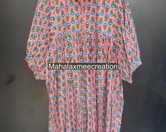 May include: A pink dress with a floral pattern in blue and green. The dress has a mandarin collar, long sleeves, and a gathered waist. The text "Mahalaxmeecreation" is visible on the dress.