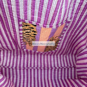 May include: A purple and white striped kantha quilt with a smaller patch of fabric sewn into the center. The patch is made of a variety of fabrics with stripes and patterns in orange, pink, and black. The text "BerryMerryGifts" is visible in the center of the patch.