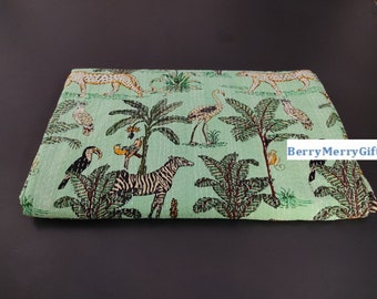 May include: A green kantha quilt with a jungle animal print. The quilt features zebras, leopards, toucans, and birds. The quilt is made of cotton and is hand-stitched.