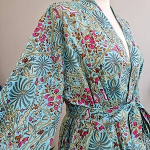May include: A teal blue robe with a floral print featuring pink, brown, and yellow accents. The robe has a long sleeve and a tie belt.