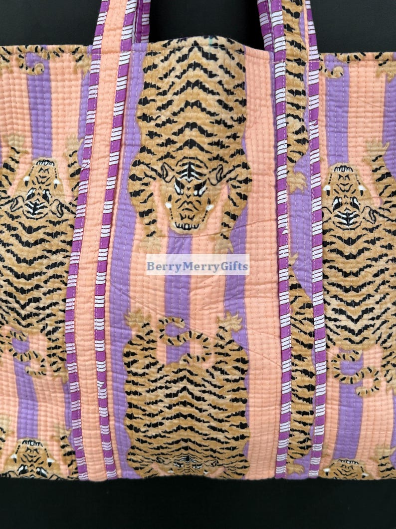 May include: A pink and purple striped tote bag with a quilted texture. The bag features a repeating pattern of brown and black tigers. The bag has two long straps.