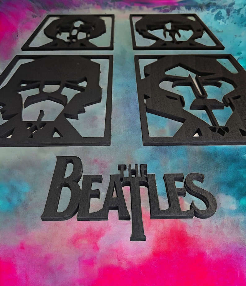 May include: Black wooden wall art featuring four square panels with band member silhouettes and the band name "The Beatles". The art is set against a colorful, abstract background.