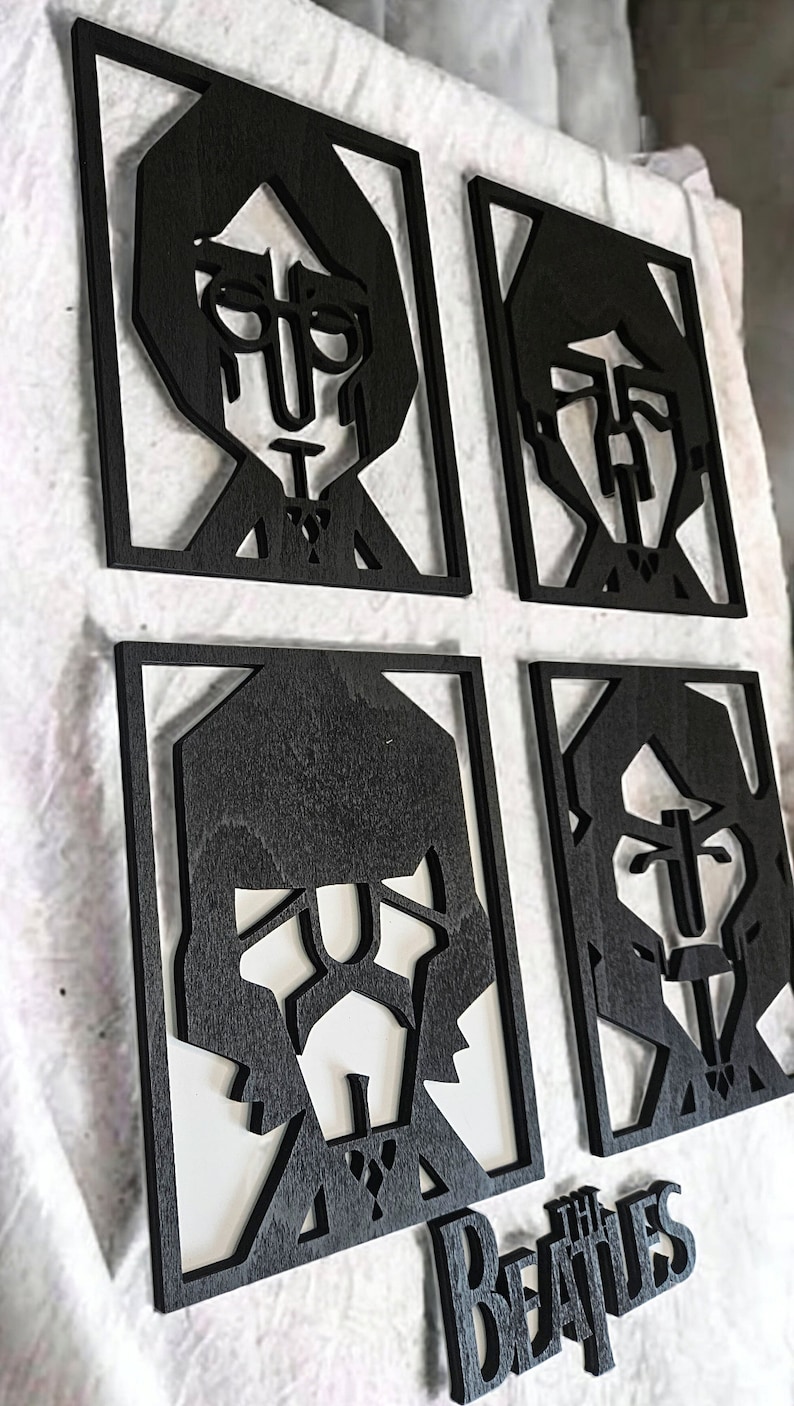 May include: Four black wooden portraits of The Beatles band members in a square frame, with the band's name below. The portraits are cut-out silhouettes with white backgrounds. The Beatles' logo is also black.