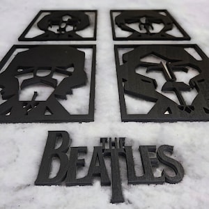 May include: Black wooden coasters featuring cut-out portraits of The Beatles band members. The word "THE BEATLES" is also displayed in a matching font. The coasters are square and the text is in a serif font.