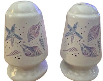 Vintage white salt and pepper shakers with pastel blue and purple shells and starfish