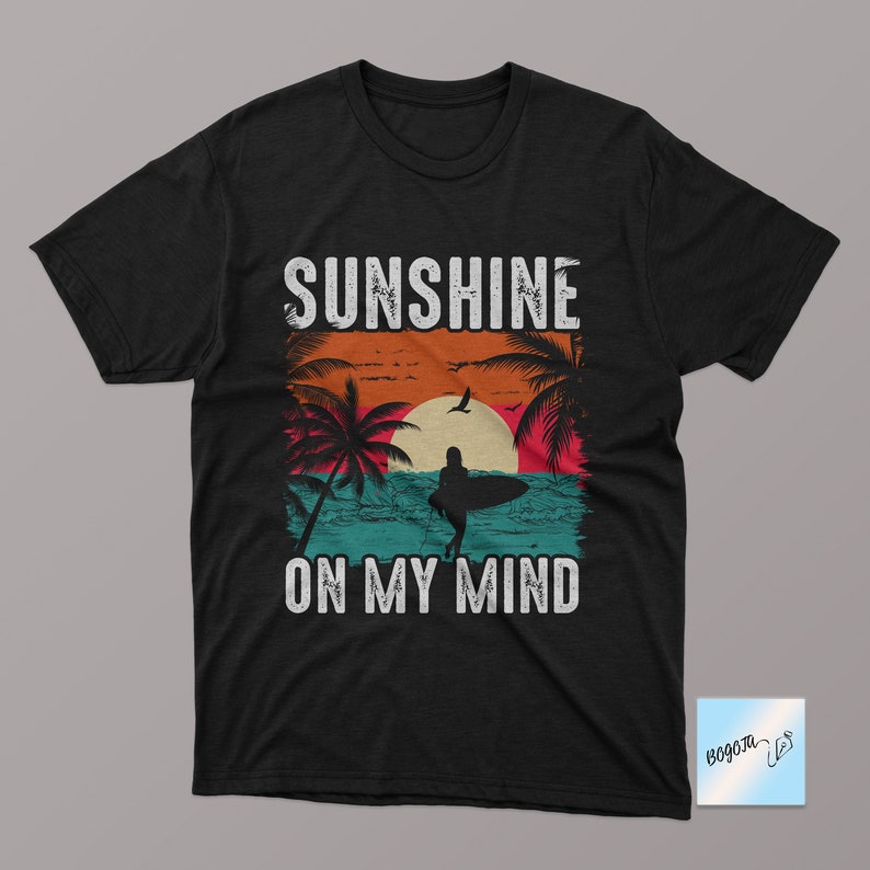 May include: Black t-shirt with a vintage-style graphic of a sunset, palm trees, and a surfer. The text "Sunshine on my mind" is printed below the graphic.