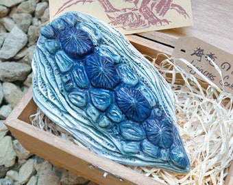 May include: A blue and white ceramic dragon scale in a wooden box with a tag that reads "Dragon Scale" in Japanese and English. The box is filled with shredded paper.