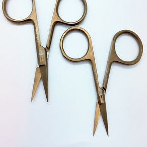 May include: Two pairs of gold-coloured cuticle scissors with the word "OLTO" engraved on the handles.