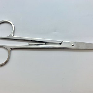 Könnte beinhalten: Eine chirurgische Schere aus Edelstahl mit einer geraden Klinge und einem kleinen, runden Griff.