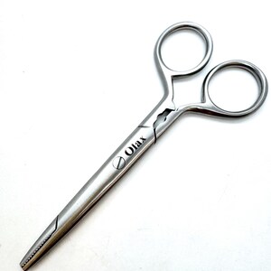 Könnte beinhalten: Eine silberne chirurgische Klemme mit einem gebogenen Griff und einer gezahnten Zange. Die Klemme ist am Griff mit "Olax" beschriftet.