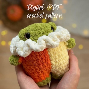 May include: Crochet pattern for a green, orange and yellow candy corn amigurumi toy. The toy has black eyes and a white crocheted collar. The text "Digital PDF crochet pattern" is displayed above the toy.