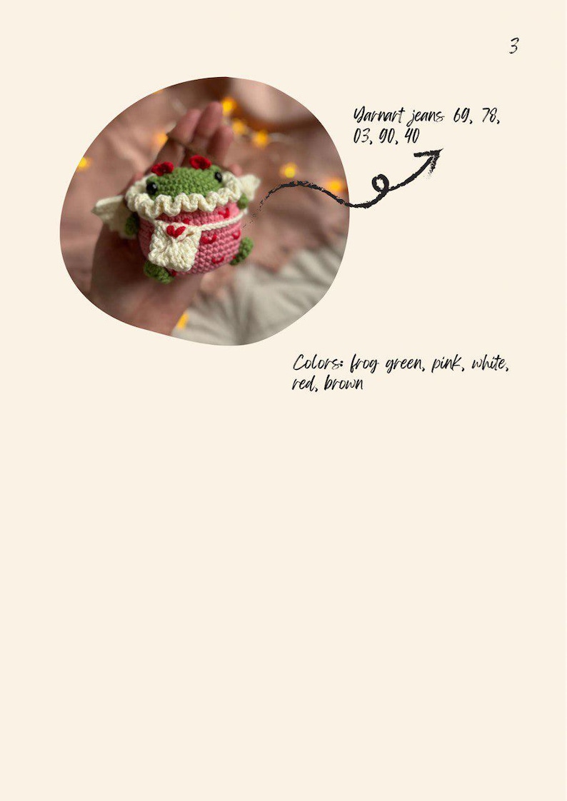 May include: A crocheted frog wearing a pink dress with white trim and a red heart. The frog is holding a white crocheted heart. The frog is green, pink, white, red, and brown.
