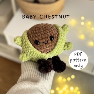 Könnte beinhalten: Ein gehäkeltes Plüschtier in Form einer Kastanie, mit einem braunen Kern und einer hellgrünen Außenschicht. Das Spielzeug hat schwarze Augen und einen lächelnden Mund. Der Text "BABY CHESTNUT" steht über dem Spielzeug, und "PDF pattern only" steht rechts.
