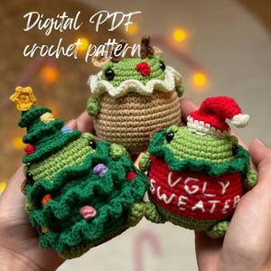 May include: Three crocheted amigurumi toys: a green Christmas tree, a green frog wearing a red "Ugly Sweater" shirt and a green frog wearing a brown reindeer costume with a red nose.