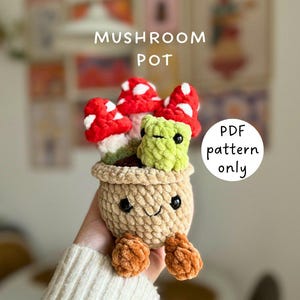May include: A crocheted mushroom pot with red and white mushrooms, a green frog, and a smiling face. The pot is tan with orange feet. The text "MUSHROOM POT" and "PDF pattern only" are visible.