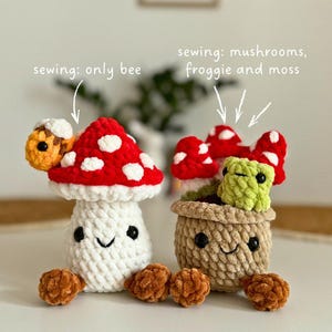 May include: Two crocheted mushroom figures. One is a white mushroom with a red cap and white spots, and a bee on top. The other is a pot with mushrooms and a green frog. The text says "sewing: only bee" and "sewing: mushrooms, froggie and moss".