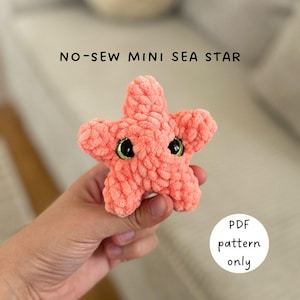 May include: A coral-colored, no-sew mini sea star, crocheted with a textured yarn. The sea star has black eyes with green irises. Text on the image reads "NO-SEW MINI SEA STAR" and "PDF pattern only".
