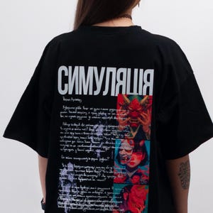 Puede incluir: Camiseta negra de gran tamaño con la palabra cirílica "СИМУЛЯЦИЯ" en blanco. La parte trasera presenta un collage de imágenes y texto, incluida la palabra "sixtynine". La camiseta tiene mangas cortas y un corte holgado.