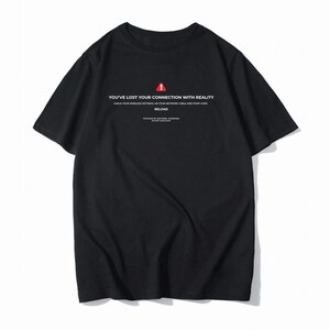 Op de afbeelding: Een zwart t-shirt met korte mouwen, voorzien van een rood waarschuwingsicoon in een driehoek en witte tekst: YOU'VE LOST YOUR CONNECTION WITH REALITY, CHECK YOUR WIRELESS SETTINGS, OR YOUR NETWORK CABLE AND START OVER, RELOAD.
