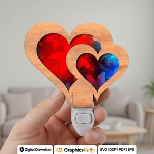 May include: A wooden night light in the shape of two overlapping hearts. The hearts have a light brown wood grain finish. The inner heart shapes are filled with red and blue abstract designs. The night light has a white base with an on/off switch.