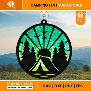 May include: A green and blue suncatcher with a silhouette of a tent, trees, and a sun. The suncatcher is round and has a suction cup for hanging.