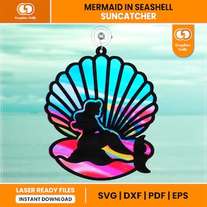 以下が含まれることがあります： 虹色の虹色の仕上げを施した貝殻のサンキャッチャーの中に、人魚のシルエットがあります。サンキャッチャーは窓に吊るすように作られています。