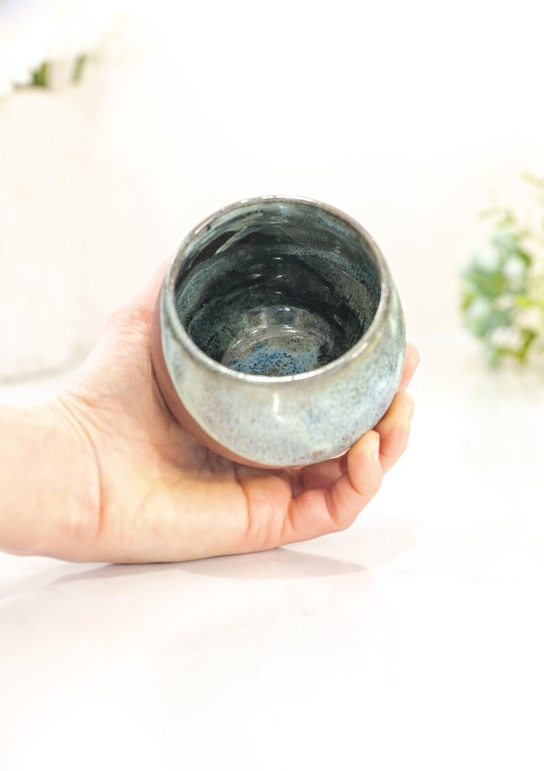 Pu&ograve; includere: Una ciotola in ceramica fatta a mano con una smaltatura unica. La ciotola, tenuta in mano, presenta una miscela di colori blu, verde e grigio. L'interno ha un aspetto pi&ugrave; scuro e strutturato, mentre l'esterno &egrave; liscio e lucido. Perfetta per servire o esporre.