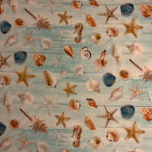 May include: A fabric pattern featuring a variety of seashells, starfish, and seahorses in shades of brown, white, and blue. The design is set against a light blue, wood-grain background, creating a beachy theme.