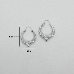 Pode incluir: Brincos de argola de prata com um design floral detalhado. Os brincos medem 3 cm de diâmetro e 3,2 cm de altura.