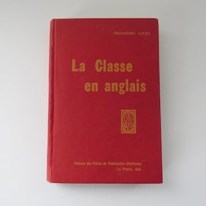 Peut inclure: Un livre rouge avec le titre "La Classe en anglais" en lettres dorées. Le livre présente un emblème doré et du texte en bas. Les mots "TROISIEME LIVRE" sont en haut.