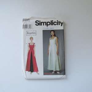 Peut inclure: Une pochette de patron de couture Simplicity 8985 avec le texte Begotten. L'emballage présente deux modèles de robe : une avec un corsage rouge et une jupe noire, et une autre entièrement blanche. La pochette inclut un code-barres et la taille H5 6-14.