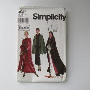 Peut inclure: Une pochette de patron de couture Simplicity, numéro 3987, taille BB L,XL. Le devant présente des illustrations de trois capes différentes : une longue cape rouge, une cape verte plus courte avec bordure en fourrure et une longue cape noire à capuche avec bordure blanche.