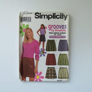 May include: Simplicity sewing pattern for skirts, with the text "grooves by Simplicity" and "New Junior Sizing!" The pattern includes various skirt styles and sizes 7/8-23/24. The package features a woman wearing a pink top and a brown skirt.