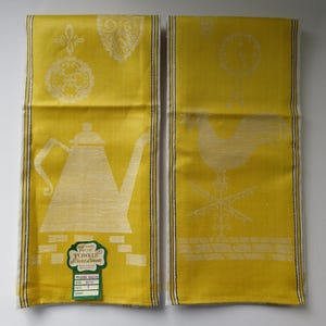 Peut inclure: Deux torchons de cuisine jaunes avec des motifs brodés blancs. Un torchon représente une théière et l'autre un coq. Les torchons portent une étiquette indiquant "Serviettes françaises brodées, pur lin".