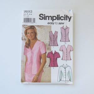 Peut inclure: Une pochette de patron de couture Simplicity 9693 pour les tailles 8-18. Le devant présente une photographie d'une personne portant une chemise rose à manches courtes et boutonnée, ainsi que quatre illustrations de variantes de chemises.