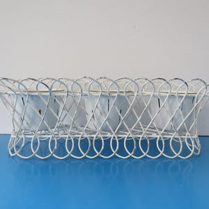 Peut inclure: Un porte-objets en fil métallique blanc avec quatre bols en émail blanc. Le porte-objets a un bord festonné décoratif et est conçu pour contenir de petits objets.