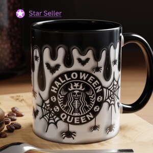 May include: Black ceramic coffee mug with a white design. The design features a dripping black substance, bats, spiders, and a Starbucks logo with the text "Halloween Queen".