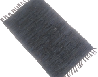 May include: A dark blue woven rug with fringe on all sides. The rug is made of a thick, textured material.