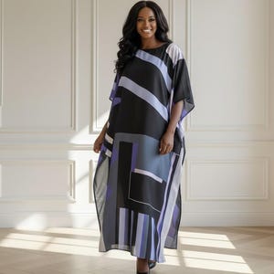May include: A flowing, geometric-patterned dress in black, gray, and lavender. The dress features a loose, caftan-style silhouette with wide sleeves. The design includes bold stripes and rectangular shapes, creating a modern, artistic look. The dress is worn with black heels.