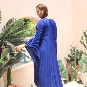 May include: A royal blue maxi dress with pleated detailing and long, flowing sleeves. The dress is made of a lightweight fabric and has a relaxed fit.