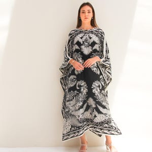 May include: A black and white maxi dress with a floral print. The dress has a loose, flowing silhouette and a scoop neckline.