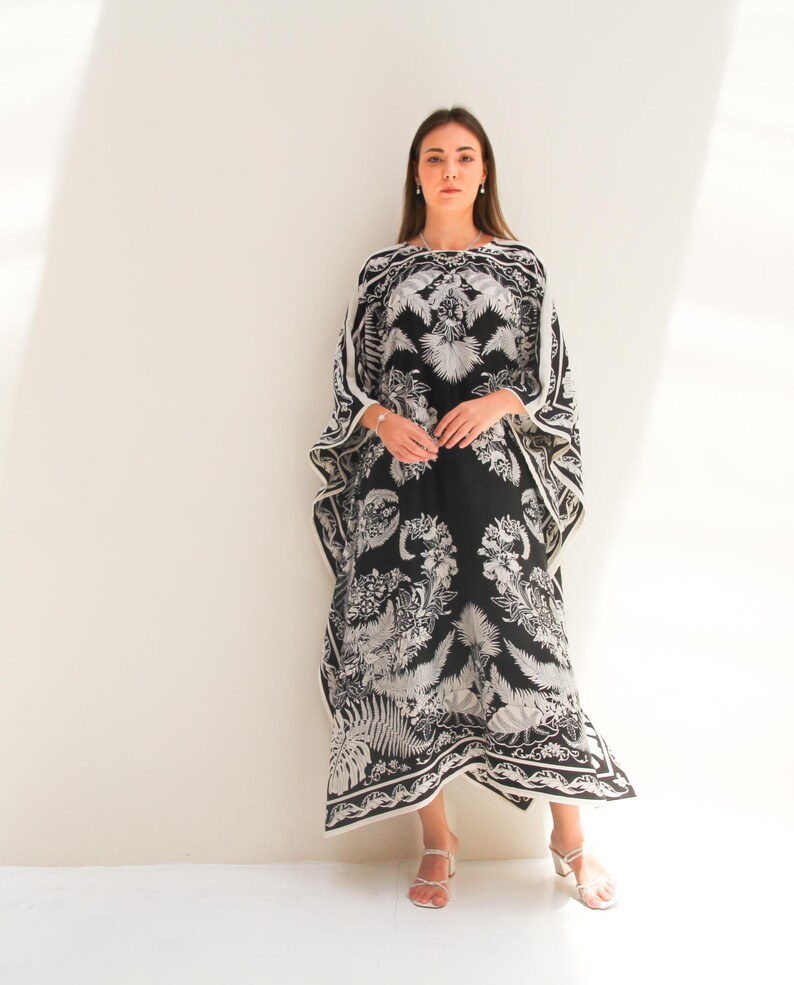 May include: A black and white maxi dress with a floral print. The dress has a loose, flowing silhouette and a scoop neckline.