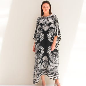 May include: A black and white maxi dress with a floral print. The dress has a loose, flowing silhouette and a scoop neckline.