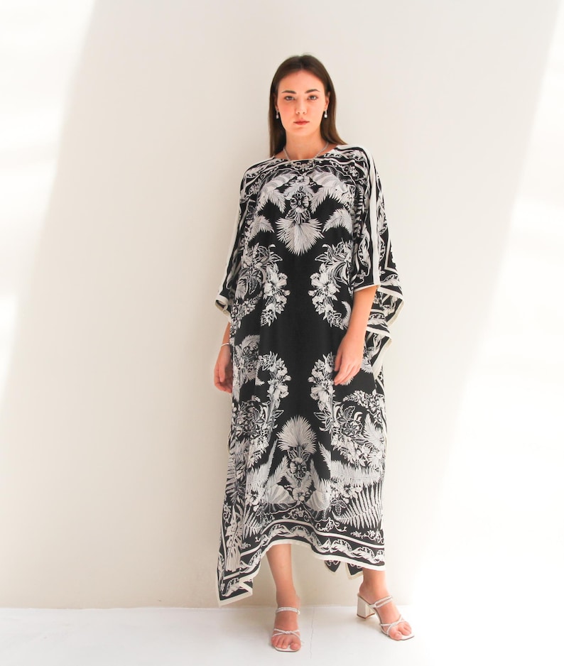 May include: A black and white maxi dress with a floral print. The dress has a loose, flowing silhouette and a scoop neckline.