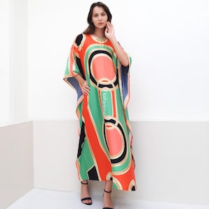 May include: A long, flowing kaftan with a geometric pattern in shades of green, orange, black, and white. The kaftan has a loose, comfortable fit and is perfect for warm weather.