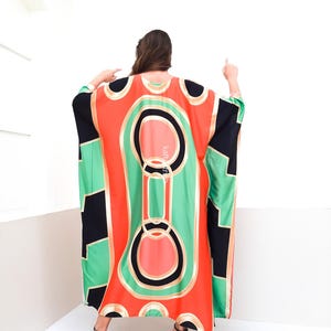 May include: A long, flowing, red, green, and black patterned kaftan with gold accents. The kaftan has a loose, comfortable fit and is perfect for warm weather.