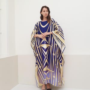 May include: A long, flowing blue and gold kaftan with a geometric pattern. The kaftan has a wide, flowing sleeve and a relaxed fit.